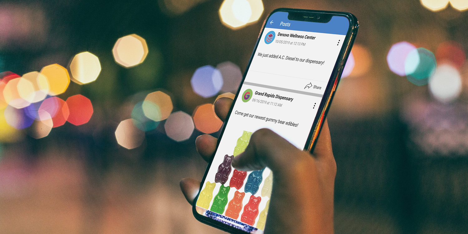 Hand holding a phone showing dispensary posts in the Weedi app
